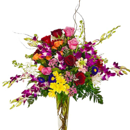 Tall mixed bouquet in a clear glass vase with roses and orchids