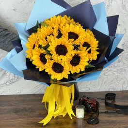 Bouquet of yellow sunflowers wrapped in blue and navy paper with a yellow ribbon