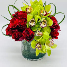 Red roses and green orchids in a glass vase