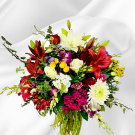 Mixed bouquet of lilies, roses, and daisies in a glass vase