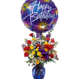 Bright mixed flower bouquet in a blue vase with a large Happy Birthday balloon