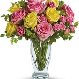 Pink and yellow roses arranged in a clear glass vase