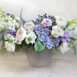 Lavender and white floral arrangement in a gray vase