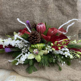 Long floral arrangement with red, white, and green blooms on burlap