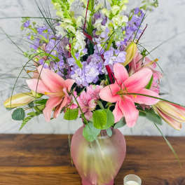 Pink lilies and lavender flowers in a frosted pink vase