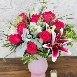 Pink roses and white lilies arranged in a pink vase
