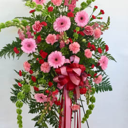 Standing floral spray with pink gerberas, carnations, and red accents