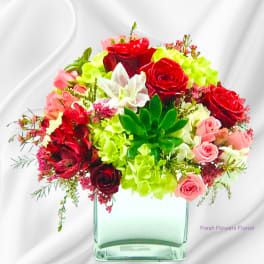 Mixed bouquet of red and pink roses with green hydrangeas in a glass vase