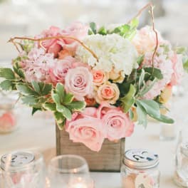 Pink and white floral centerpiece in a wooden box on a table
