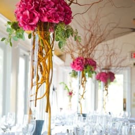 Tall pink floral centerpieces in clear glass vases on a banquet table