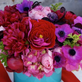 Bright pink and red flower arrangement in a turquoise box
