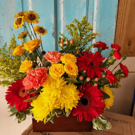 Bright mixed bouquet with red gerberas, yellow roses, and carnations in a box