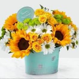 Sunflowers, yellow roses, and white daisies in a turquoise container