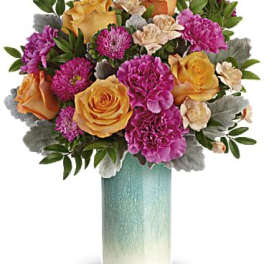 Bouquet of orange and pink flowers in a tall turquoise vase