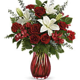 Red roses and white lilies in a red glass vase