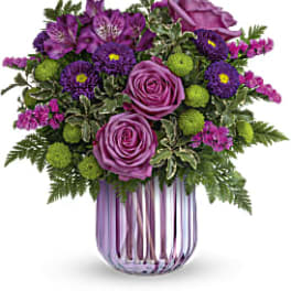 Purple roses and mixed purple flowers in a striped glass vase
