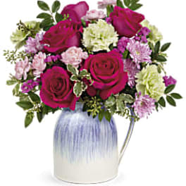 Bouquet of magenta roses and pastel carnations in a blue-and-white vase