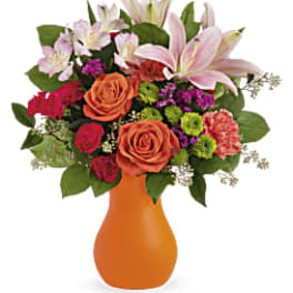 Mixed bouquet of pink lilies, roses, and carnations in an orange vase