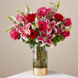 Pink lilies and red roses arranged in a clear glass vase