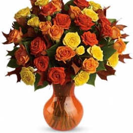 Bouquet of orange, red, and yellow roses in an amber vase