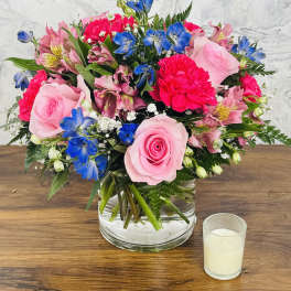 Pink and blue mixed flower arrangement in a clear glass vase
