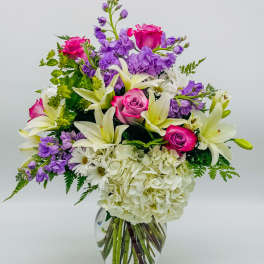 Mixed bouquet of pink roses, white lilies, purple flowers in a glass vase