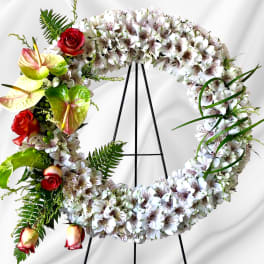 Circular floral wreath on an easel with white blooms and red roses