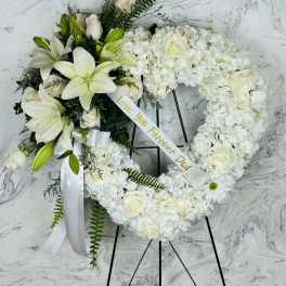 White floral funeral wreath on a black stand with a ribbon