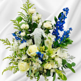 White roses and blue flowers arranged around a white statue