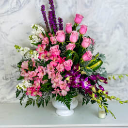 Pink roses and mixed blooms arranged in a white vase