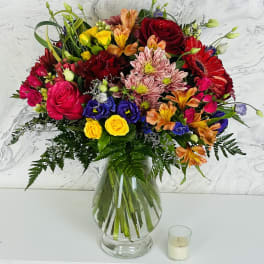 Colorful mixed bouquet in a clear glass vase with roses and daisies