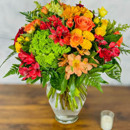 Mixed bouquet of roses, alstroemeria, and chrysanthemums in a glass vase
