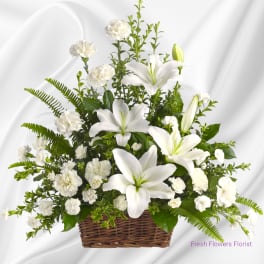 White lilies and carnations arranged in a wicker basket