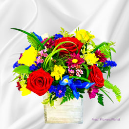 Bright mixed bouquet of roses and daisies in a square vase