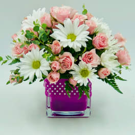 Pink roses and white daisies arranged in a purple glass vase