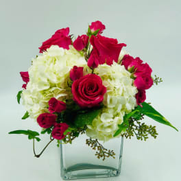 Pink roses and white hydrangeas arranged in a clear glass vase