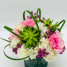 Pink and white flowers with a green succulent in a glass vase
