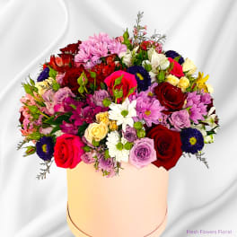 Mixed bouquet of roses, daisies, and alstroemeria in a round box