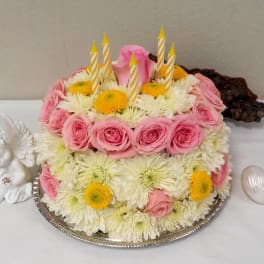 Pink roses and white daisies arranged as a cake with candles