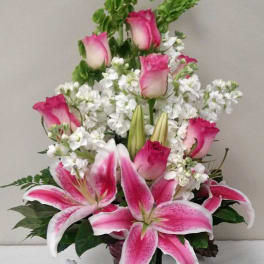 Pink roses and lilies arranged in a vase with white filler flowers