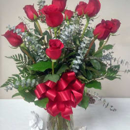 Red roses in a glass vase with a large red ribbon