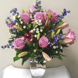 Pink roses and lilies arranged in a clear glass vase