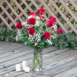 Red roses in a clear glass vase with white filler flowers