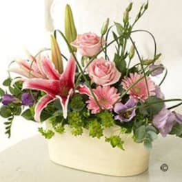 Pink lilies and roses in a white oval vase