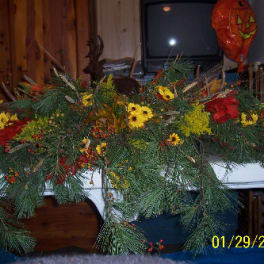 Long floral garland with red and yellow flowers draped over a white surface