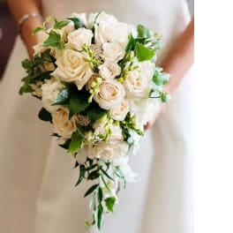 Bride holding a cascading bouquet of white roses and greenery
