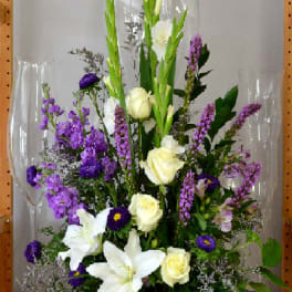 Tall white vase arrangement with white lilies, cream roses, and purple flowers