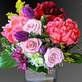 Mixed pink, red, and purple bouquet in a clear square vase