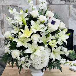 White lilies and roses arranged in a white pedestal vase