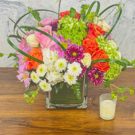 Mixed bouquet of roses, chrysanthemums, and hydrangea in a square glass vase
